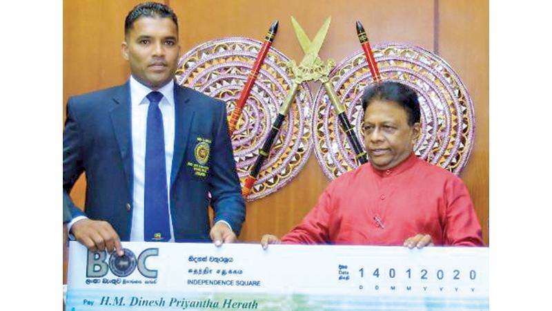 Champion Para athlete Dinesh Herath receiving Rs. 4.2 million award from the Sport Minister Dullas Alahapperuma at the Sport Ministry
