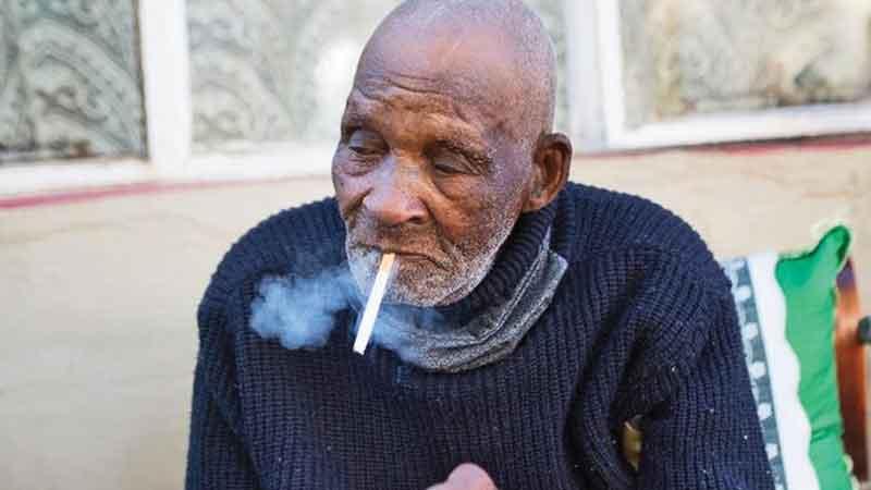 Fredie Blom enjoys a cigarette as he celebrates his 116th birthday at his home in Delft, near Cape Town (AFP)