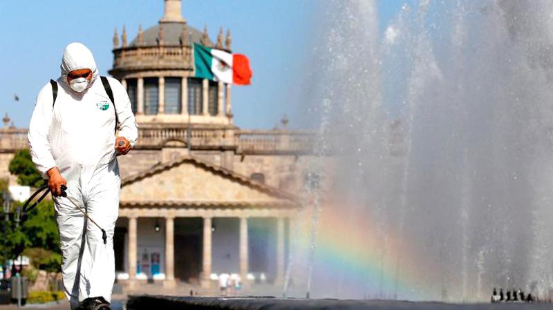 A worker wearing a protective suit sprays disinfectant during a campaign to sanitize public spaces in Guadalajara, Mexico