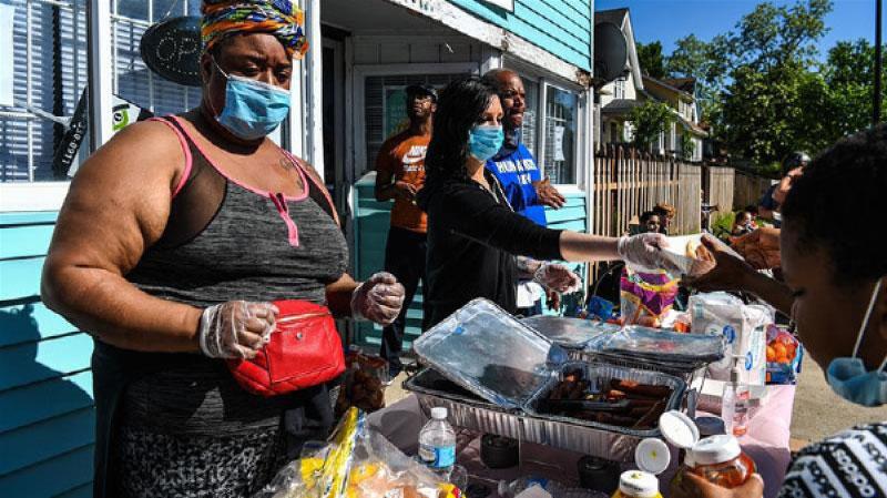 People cook and distribute free food and water to the protestors at a makeshift memorial in honour of George Floyd in the United States