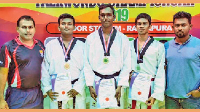 Akila Upamal (third from left) his coach Priyantha Kumara (left) and master in charge Priyadharshana Cooray (right) pose for a picture at the Sri Lanka Schools Taekwondo Championship held in Ratnapura