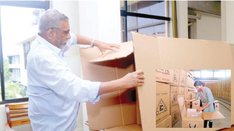 Counting  of ballot papers will not take place the same day this time, due to  the health guidelines of the Covid-19 pandemic. Here the Election Commission Chairman Mahinda Deshapriya shows the Sunday Observer  photojournalist where the ballot boxes will be sealed until they are  opened for counting on August 6. Right: A woman member of the poll staff at the  D.S. Senanayake College making the final preparations. Including health officials, almost 400,000 staff will be deployed  on election duty this year. 