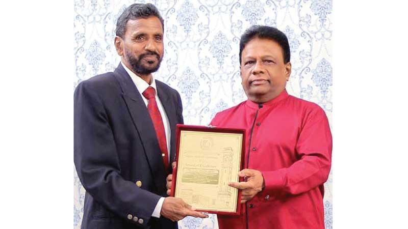 National athletic coach YK Kularatne receiving his special merit award from Minister of Power Dullas Alahapperuma