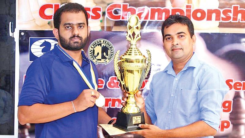 99X Technology Application Security Engineer Pranieth Chandrasekara (left) receives the trophy from Chess Federation of Sri Lanka Treasurer Irosh Jayasinghe.