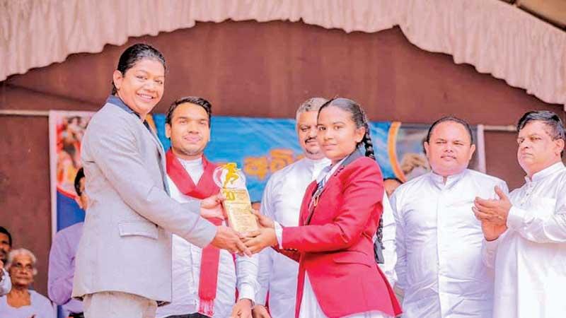 Susanthika Jayasinghe receiving a special replica from her first school Uduwaka Kanishta Vidyalaya presented by a student    in the presence of Sports Minister Namal Rajapaksa and State Minister Thenuka Vidanagamage