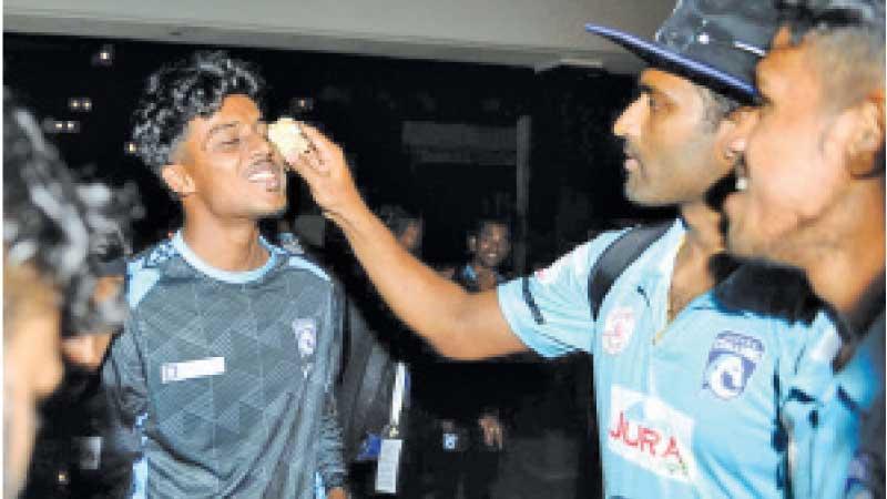 Jaffna Stallions captain Thisara Perera holds a piece of cake to  Viyaskanth in the presence of team mates