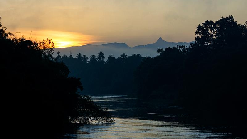 Sunrise over the Sri Pada mountain range seen through Kelani Ganga at dawn in Hanwella