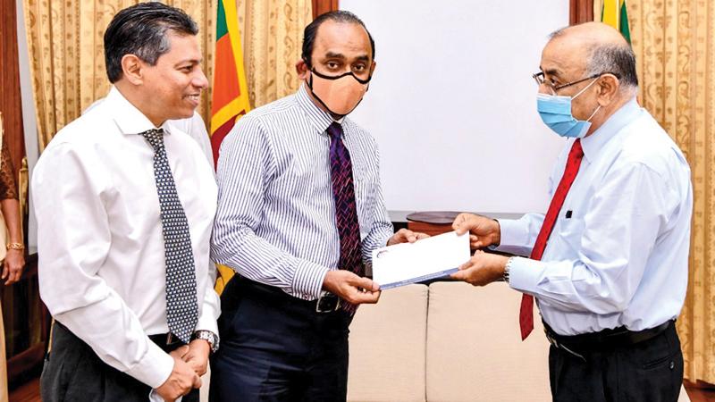 The Chairman of the People’s Bank and People’s Leasing, Sujeewa Rajapakse presents a cheque for Rs. 5 million to the Secretary to the President Dr. P. B. Jayasundara. Former CEO and GM of PLC, Sabry Ibrahim looks on. 