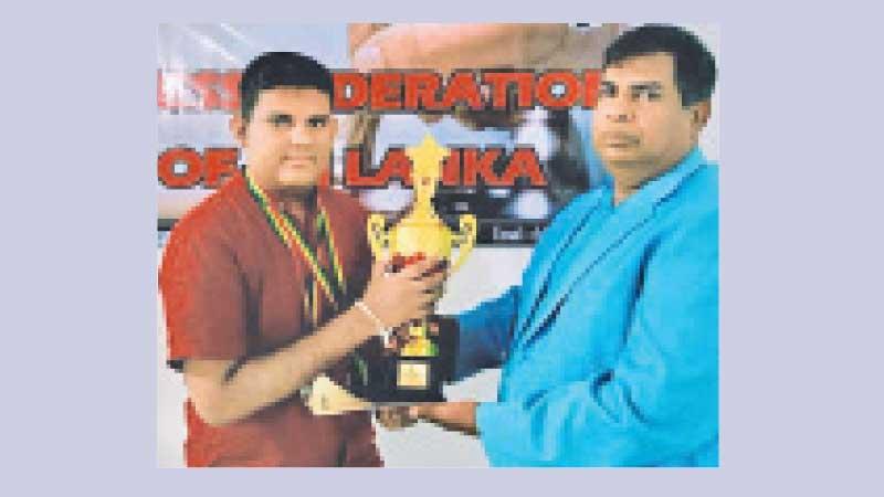 Sri Lankan Chess Grand Prix champion Ranindu Liyanage receiving the Champions trophy from the chief guest CFSL president Luxman Wijesuriya