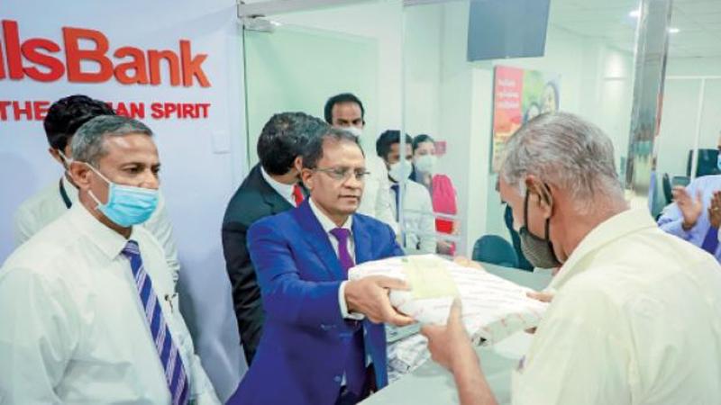 Managing Director and CEO of Cargills Bank, Senarath Bandara makes the first transaction following the opening of the branch.