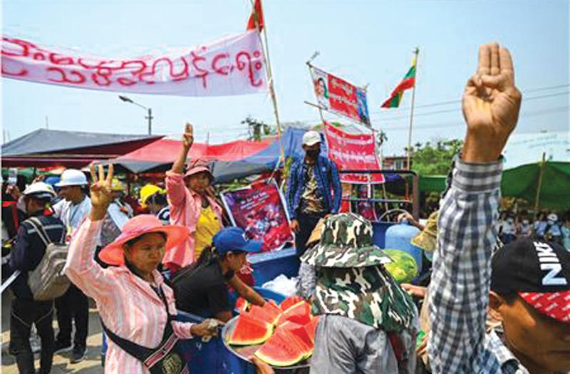 Mar 13 - People distributing watermelons to protesters make the three-finger salute in Yangon as security forces continue to crackdown on demonstrations against the military coup. - AFP