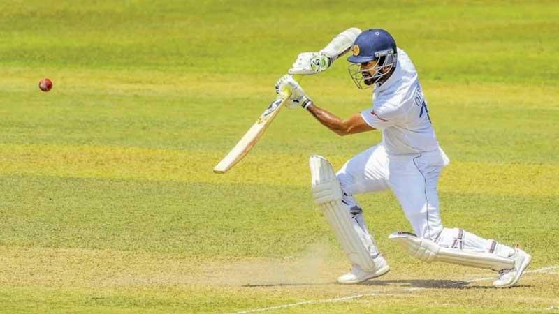 Dimuth Karunaratne raises his bat after reaching a double century