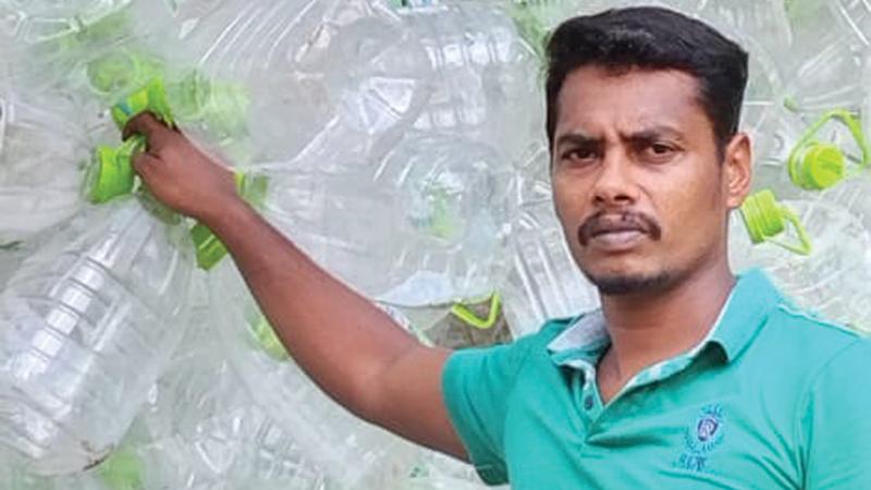 Mahesh standing beside the collectedPET plastic waste.