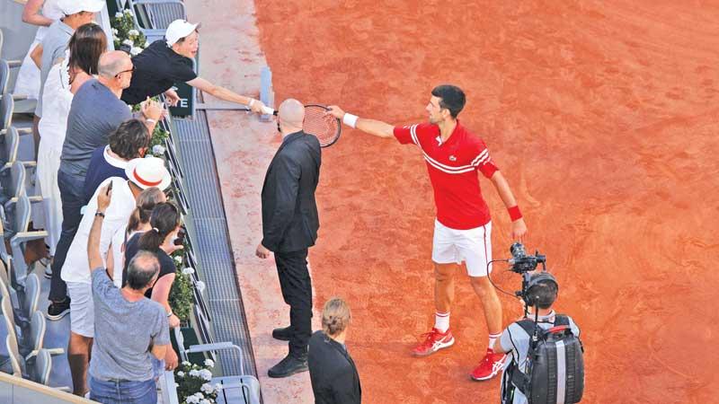 Novak Djokovic gives his Grand Slam winning racquet to a young boy in the crowd