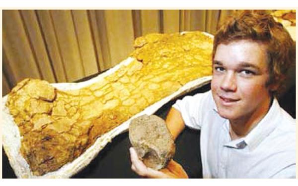  Sandy Mackenzie holds the small fossil he found next to a larger fossilised bone discovered by scientists during a dig on his family’s sheep and cattle property near Eromanga in Queensland
