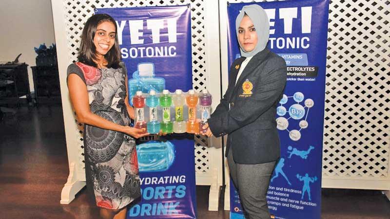 Director Yeti Nishelli Perera (left) handing over an isotonic sports drink pack to the captain of the Sri Lanka women’s squash team Fathum Issadeen 