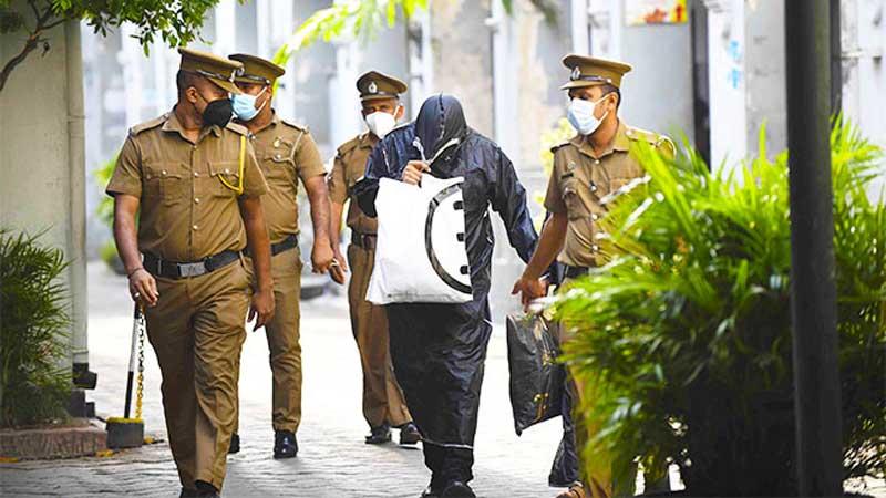 A suspect in the alleged rape of a 15-year-old girl at Mount Lavinia covers his face from the media prior to a court appearance