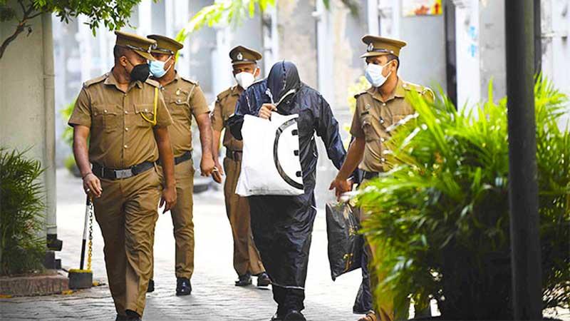 A suspect in the alleged rape of a 15-year-old girl at Mount Lavinia covers his face from the media prior to a court appearance