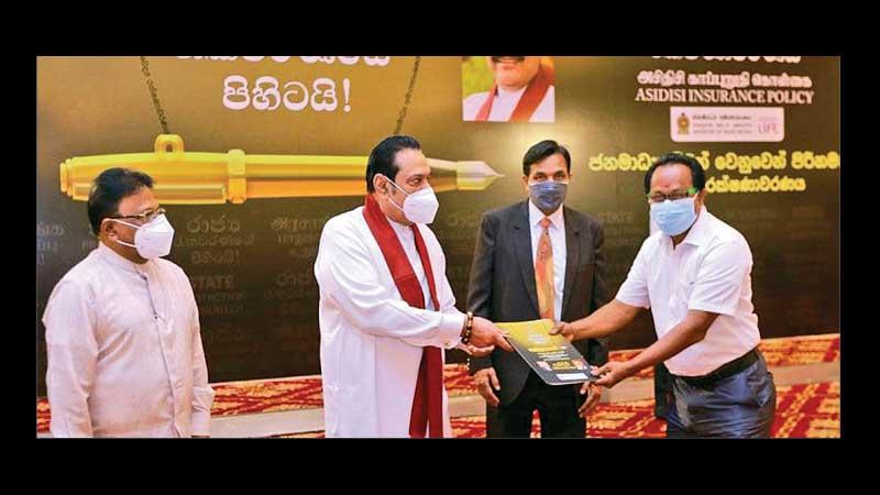Thinakaran News Editor Ashok Kumar receives the insurance cover from Prime Minister Mahinda Rajapaksa, while Mass Media Minister Dullas Alahapperuma and Media Ministry Secretary Jagath P. Wijeweera look on