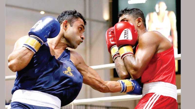 Army’s Bandula Rajakaruna (blue) lands a body blow on Navy’s DLPR Kumara in the light welter weight final during the selection meet at the Royal MAS Arena (Pix by Sulochana Gamage)