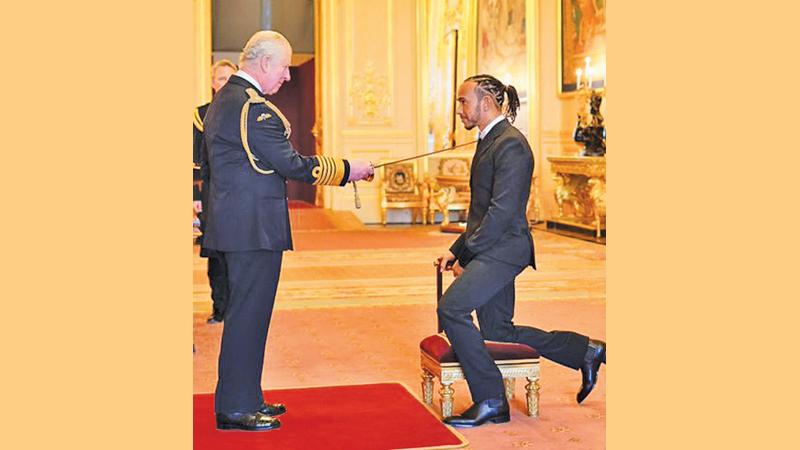 Lewis Hamilton being knighted by Britain’s Prince Charles