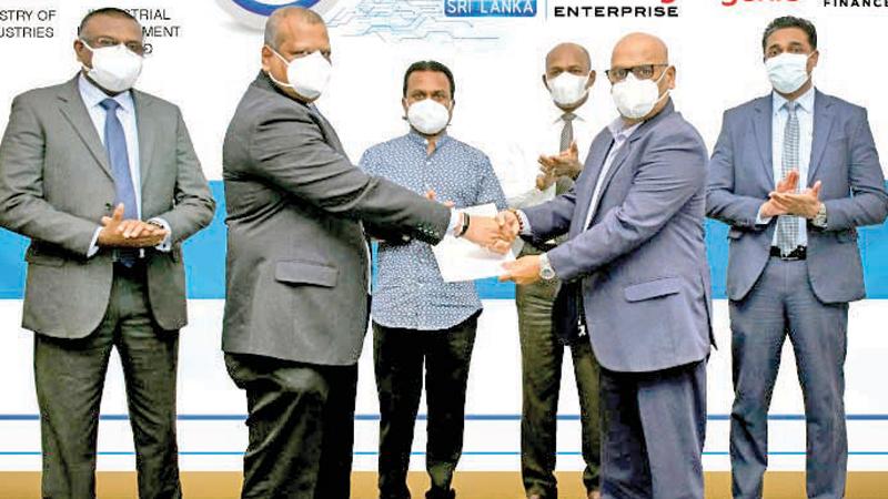 Group Chief Officer of Dialog Enterprise, Navin Pieris presents the Title Sponsorship confirmation to Chairman, Industrial Development Board, Upasena Dissanayake. Minister Wimal Weerawansa, Secretary, Ministry of Industries, Gen (Rtd) Daya Ratnayaka, Head of Emerging Business, Dialog Axiata, Channa Amarasekara, and Senior General Manager, Brand and Media, Dialog Axiata, Harsha Samaranayake look on.