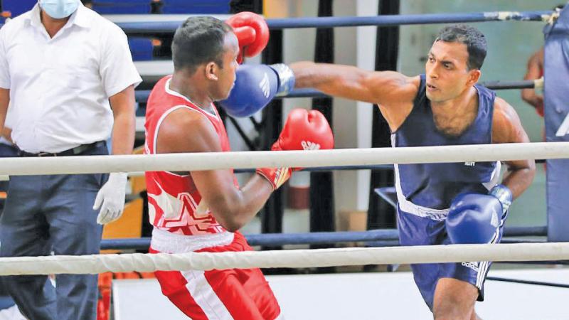 Air Force’s IPDC Udayakumara lands a solid blow on Army’s PMLL Chandrabandara on his way to win the Welter weight (under 67kg) final at the Layton Cup Boxing Championship at Royal MAS Arena yesterday. (Pic by Jagath Iroshana)