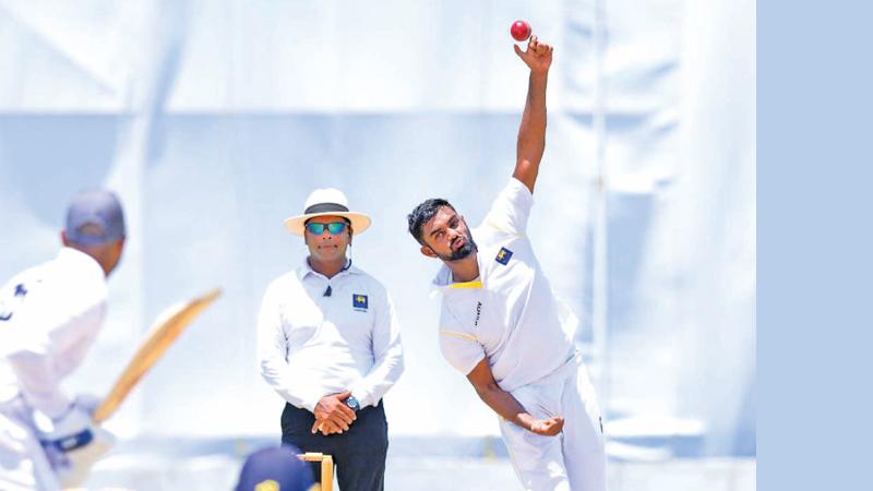 Kandy leg spinner Lasith Embuldeniya bowls during his four-wicket haul while umpire Prageeth Rambukwella looks on (Picture SLC)