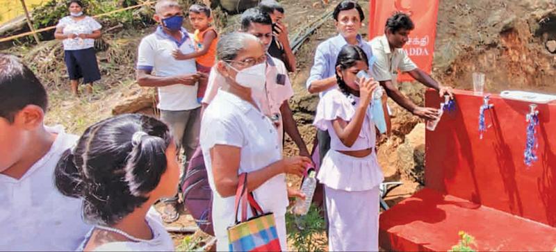 Philanthropist Harsha Dias watches a little girl sip a glass of purified water