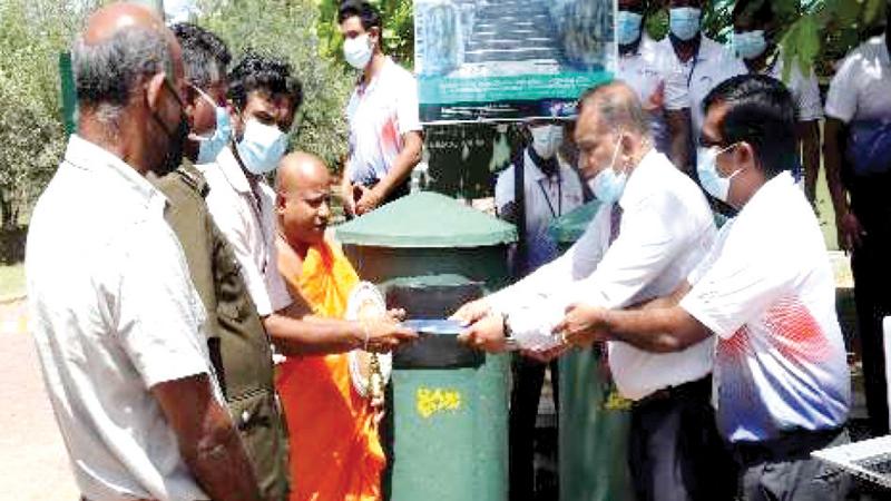Assistant Regional Manager, People’s Leasing and Finance, Susil Priyantha presents the waste bins to Solosmasthana Bhaarakara Ven. Kanda Ketiya Aththadassi Thera.