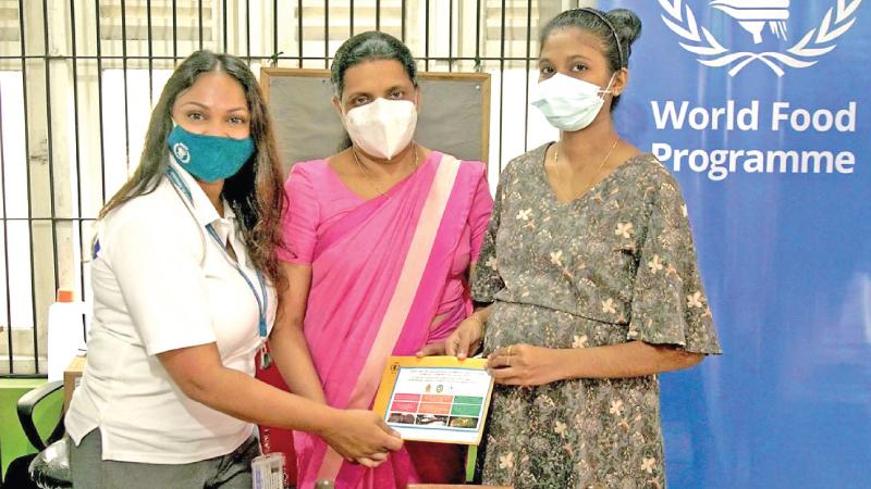 A pregnant mother receives a voucher from Rushini Perera - Head of Resilience, Emergencies and Social Protection, World Food Program, Sri Lanka and Dr. L.N.N. Vithana – Medical Officer of the Maternity and Child Welfare Centre in Wasala Road, Colombo 13.