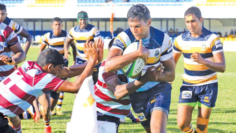 St. Peter’s College captain and fly-half Sudesh Jayawickrema shoves his way against the Dharmaraja College defence