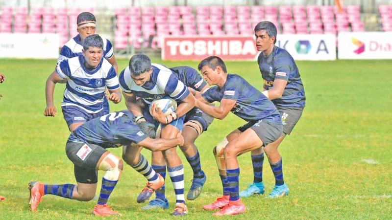 Three defenders of S. Thomas' College hold back the robust St. Joseph's College Number Eight Marasinghe in their inter-school rugby match at Havelock Park yesterday (Pic Thepapare team)