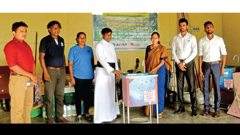 Divisional Secretary Akuressa K. G. D. Anoja accepts the gift of relief equipment from Rev. Lasantha Sanjeewa Director CARITAS SED Galle