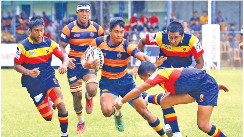 Royal College scrum half Kaveen Sasanga attempts to stave off a tackle from a Trinity College defender in the first leg of the Bradby Shield rugby encounter at the Royal Sports Complex ground in Colombo (Pic by Chinthaka Kumarasinghe)
