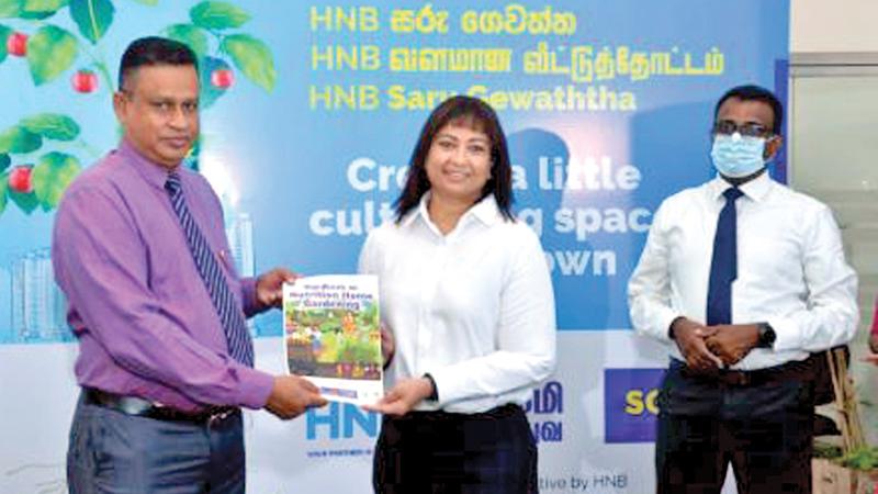 HNB Deputy General Manager CHRO/ CTO, L. Chiranthi Cooray, presents Agriculture Department Commissioner General, A.H.M.L. Abeyrathna, a handbook on home gardening developed by HNB.