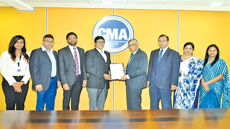 The President of CMA Sri Lanka Prof. Lakshman R. Watawala presents the MoU to CEO of Infomate, Jehan Perinpanayagam., Officials of CMA Sri Lanka and Infomate look on.