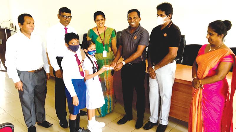 Manager, CSR and Corporate Sustainability, Nuwan Pathirana presents seed packets to a student. Zonal Education Director, Piliyandala,  Kumudu Hemamali De Silva, Manager, Sampath Bank, Piliyandala Branch,  Ravi Silva and  Deputy Director, Planning, Zonal Education Office, Piliyandala, Geetha Priyadarshani look on. 