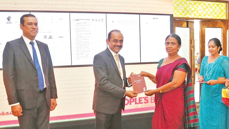 Chairman of the People’s Bank Sujeewa Rajapakse symbolically presents a Ethera Sisu Diriya progress report to a principal. CEO and General Manager Ranjith Kodituwakku looks on.