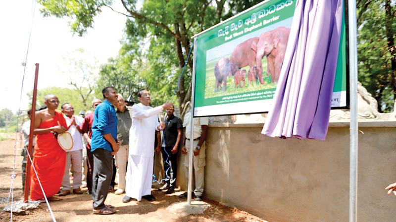 The chief guest Karu Jayasuriya unveiling the elephant electric fence in Bandiwewa. Head of Cinnamon Nature Trails, Chitral Jayatillike and invitees look on.