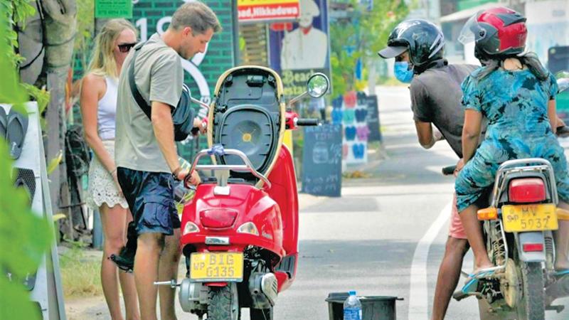 Passersby stop to help out the tourists posing with a broken motorbike.