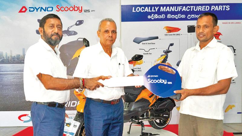 Director Inventive Automobiles, Lester Carron and Director, Dyno Innovations, Sandeepa Wijesinghe present the first Dyno Scooby 125 EFi scooter to A. P. Kumara 
