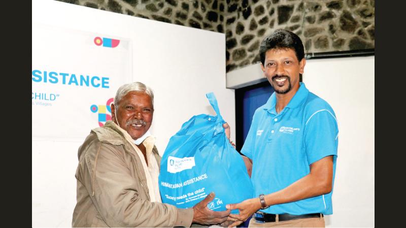 National Director SOS Children’s Villages Sri Lanka Divakar Ratnadurai hands over an educational pack to a student at the Kahapola School