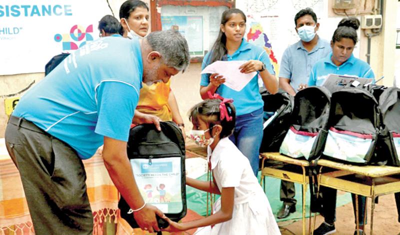 National Director SOS Children’s Villages Divakar Ratnadurai hands over an educational pack to a student at the Kahapola School