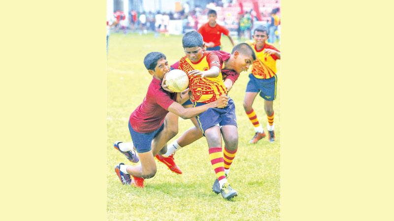 Arkesh Perera from President’s College Rajagiriya is tackled by two defenders from Siri Piyarathana Padukka in one of the matches at Havelock Park (Pic by Chainthaka Kumarasinghe)
