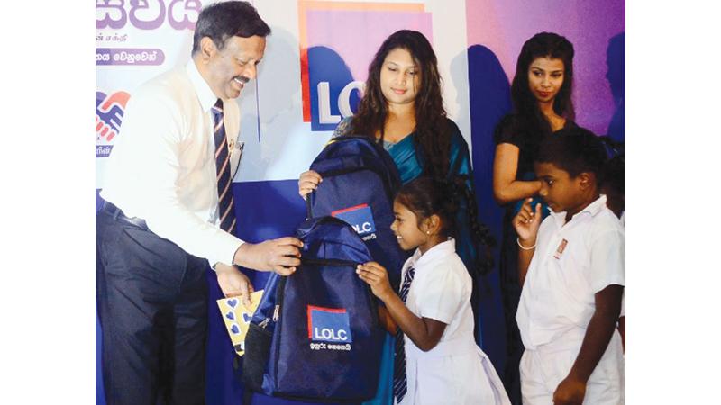 Group Managing Director and CEO of LOLC Holdings Kapila Jayawardena presents packs to schoolchildren. Pic: Wasitha Patabandige