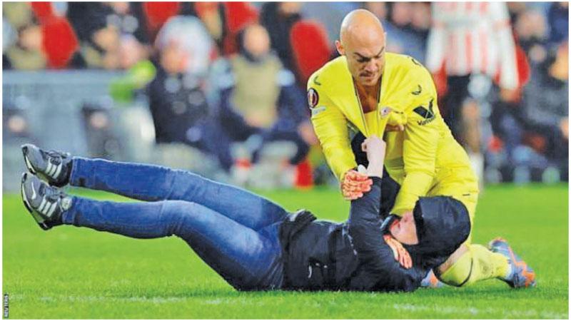 Sevilla keeper Marko Dmitrovic wrestles the fan to the ground