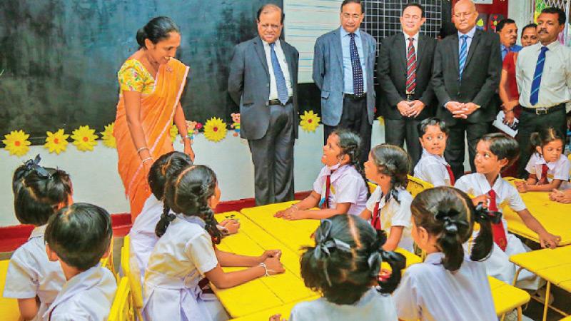 Education Minister Susil Premajayantha and Western Province Governor and officials at a classroom yesterday.
