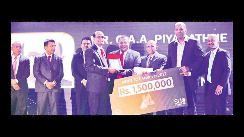 MDRT Top Achiever 2022 G. A. A. Piyaratne receives a cash reward from Director, SLIC, Dr. Kithsiri Manchnayakke. Director, SLIC, Dushmantha Thotawatte, CEO, SLIC Chandana L. Aluthgama and the Corporate Management of SLIC look on.