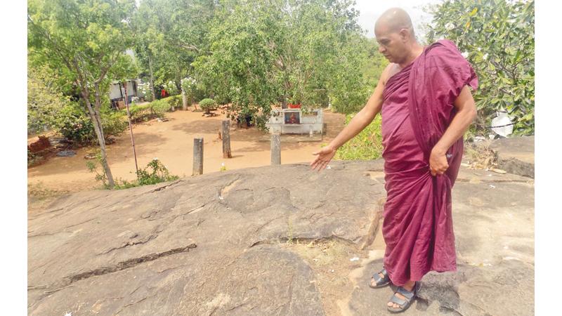Chief Incumbent Ven. Arampola Sugathawansa Thera showing a stone inscription